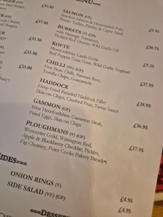 Close-up of a pub menu showing dishes including haddock, gammon, and Ploughman’s lunch with prices.